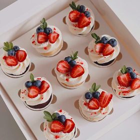 Капкейки з вершковим кремом, полуницею й чорницею в коробці